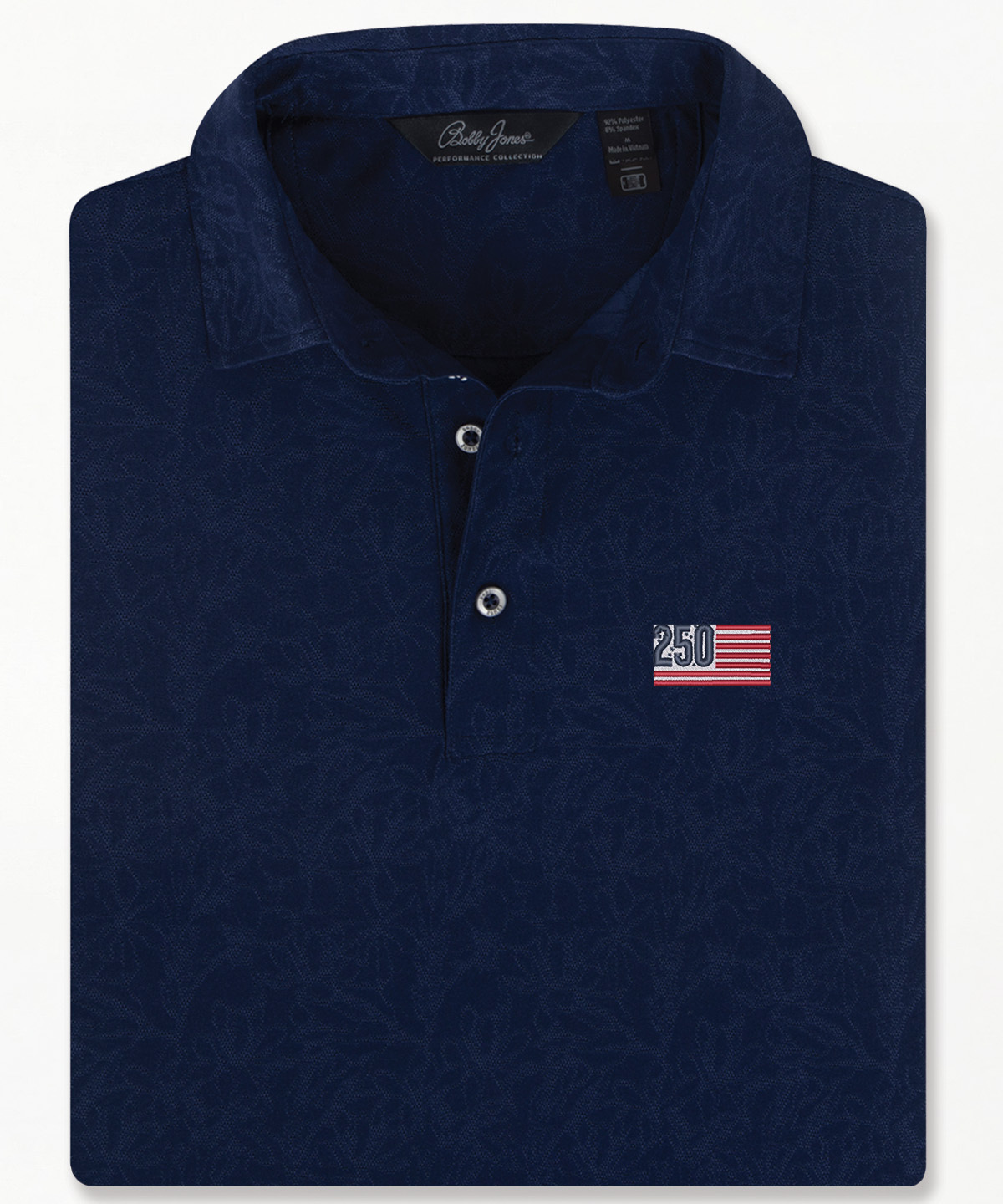 Bobby Jones men’s navy jacquard golf polo with subtle floral pattern, short sleeves, and three-button placket, folded to highlight textured design and tailored collar.