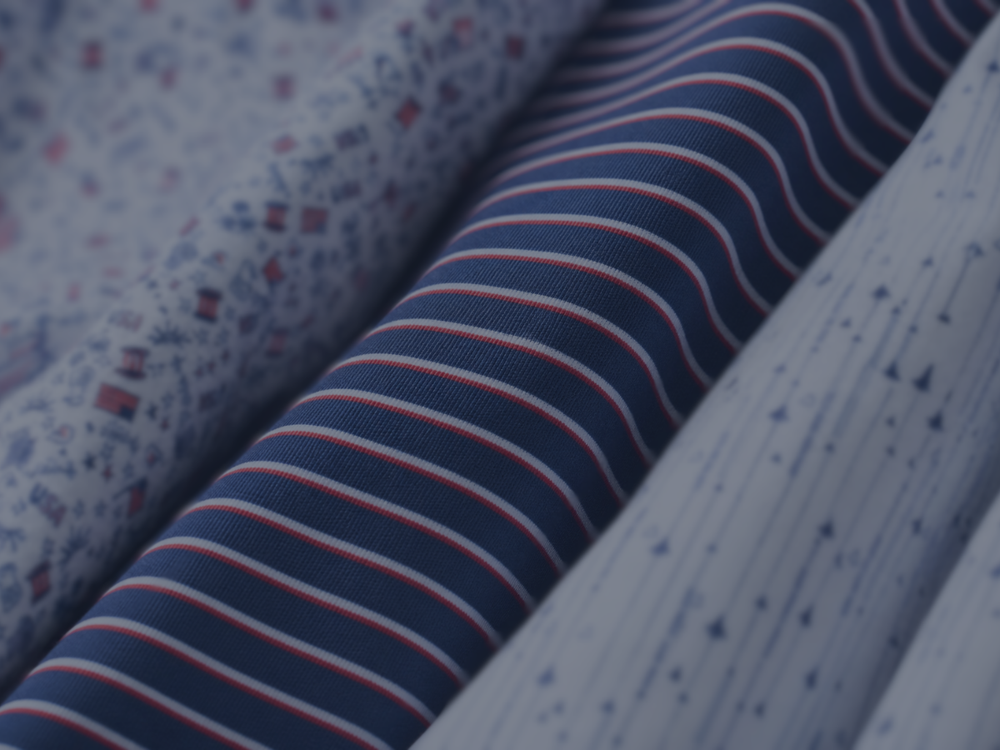 Bobby Jones Patriot Collection featuring close-up red, white and navy golf apparel fabrics beside a golfer wearing a white patterned polo with a 250 chest logo.
